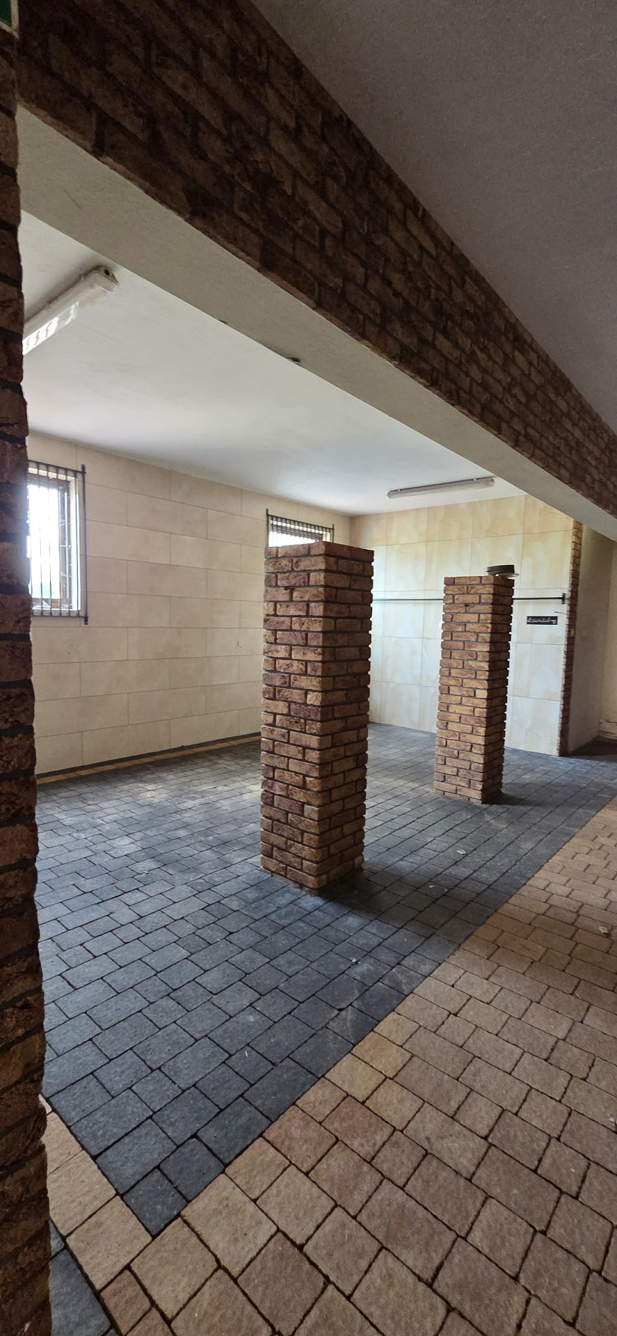 Zadaszona hala z ceglanymi filarami i kostką brukową